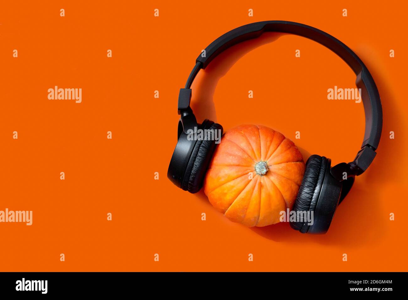 zucca su sfondo arancione. cuffie wireless sulla zucca. preparazione per l'halloween Foto Stock