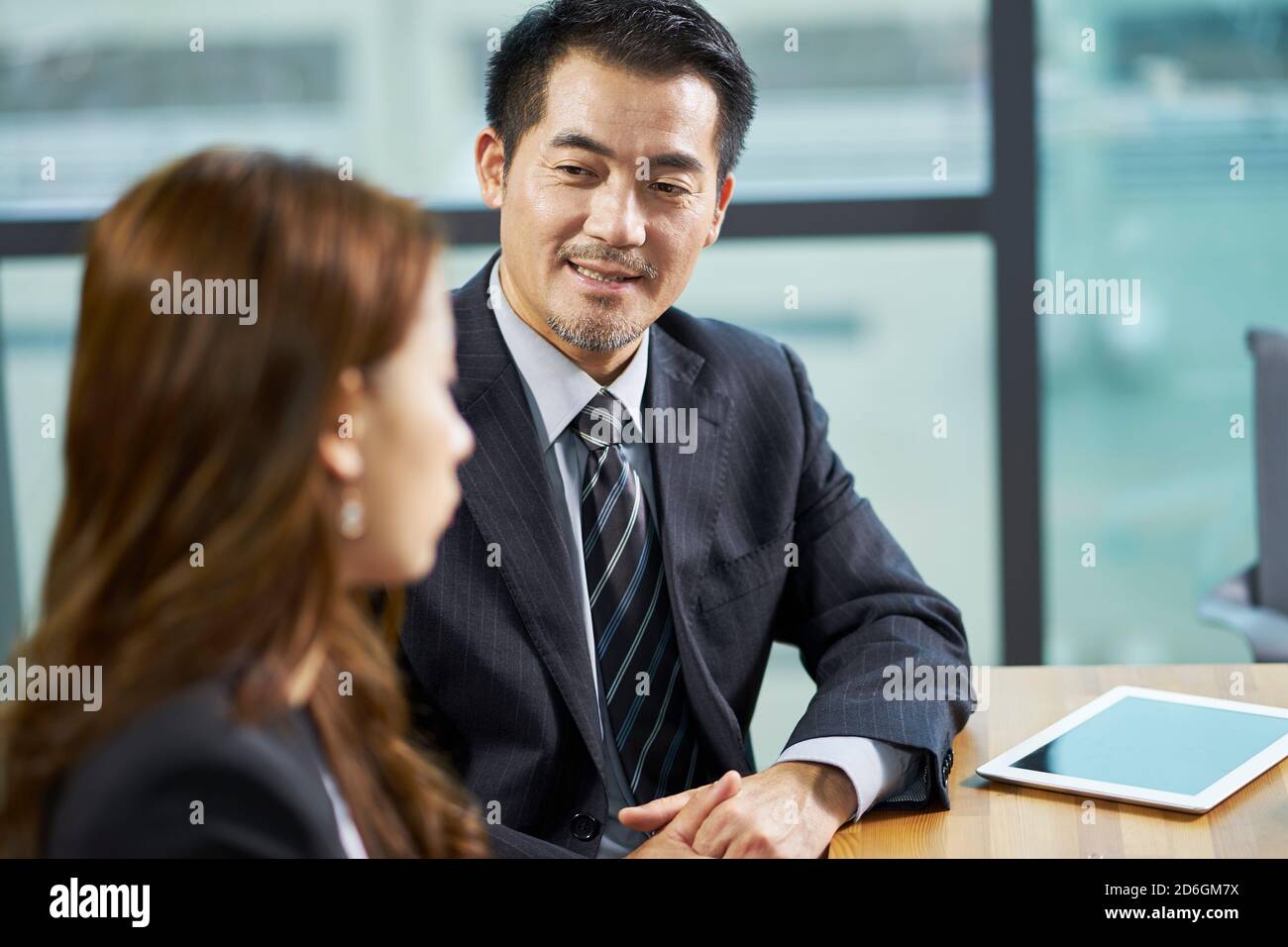 due dirigenti aziendali asiatici che hanno una conversazione in ufficio Foto Stock