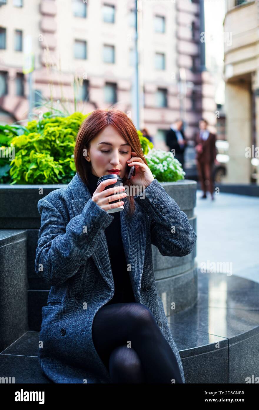 La donna d'affari beve il caffè mentre parla al telefono. Foto Stock
