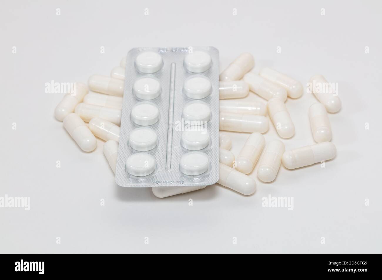 Immagine ad alto angolo di varie pillole bianche su sfondo bianco. Alcuni di loro sono fuori fuoco. Business farmaceutico e vendita di farmaci concetti. Foto Stock