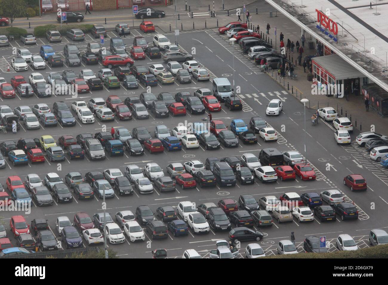 Una fotografia dall'alto che guarda in basso su un parcheggio Tesco, pieno di veicoli e acquirenti. Foto Stock