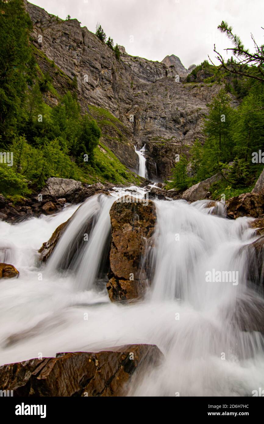 Piccole cascate che sgorgano in una foresta verde a lunga esposizione. Acqua in movimento - Alpi svizzere Foto Stock