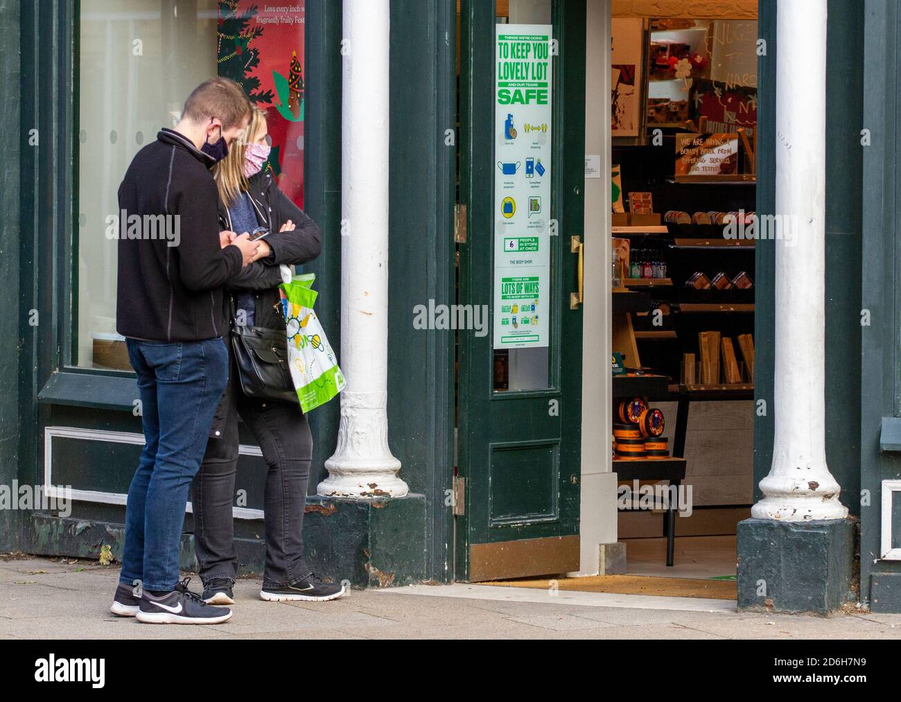Dundee, Tayside, Scozia, Regno Unito. 17 Ott 2020. Regno Unito tempo: Sole autunnale con una fresca brezza attraverso la Scozia Nord-Est, temperature massime 10°C. Due giovani clienti che si accodano all'esterno del Body Shop indossando mascherine ed essendo consapevoli delle norme Stay Safe nel centro città di Dundee durante le restrizioni di blocco Covid-19. Credit: Dundee Photographics/Alamy Live News Foto Stock