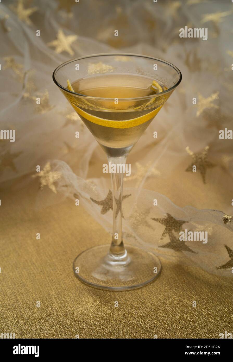 Cocktail alla vodka Martini con limoni in twist su tessuto dorato davanti a un panno bianco stellato Foto Stock