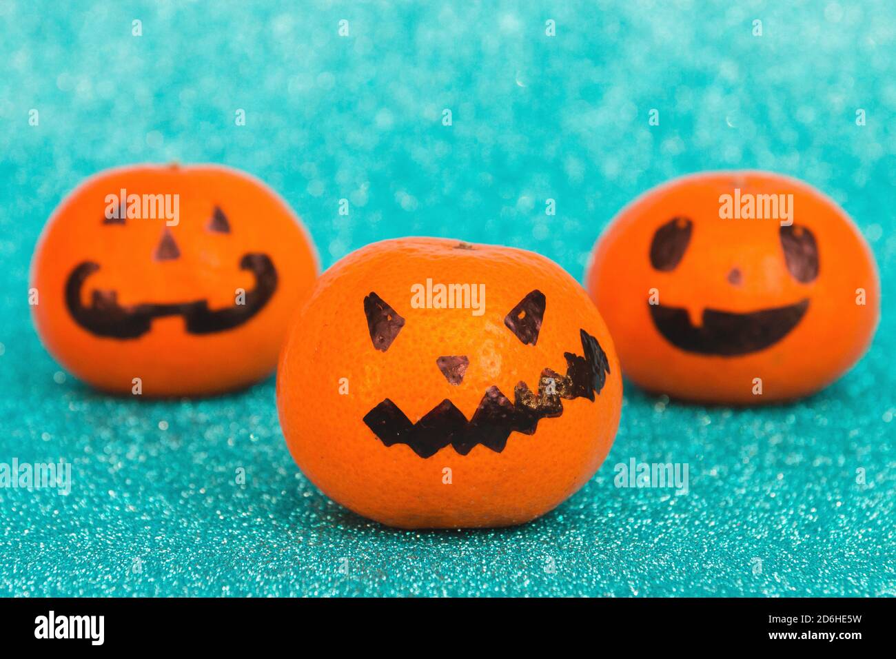 Arancione brillante Halloween spaventoso mandarini emozioni volti su sfondo blu brillante, fuoco selettivo. Foto Stock