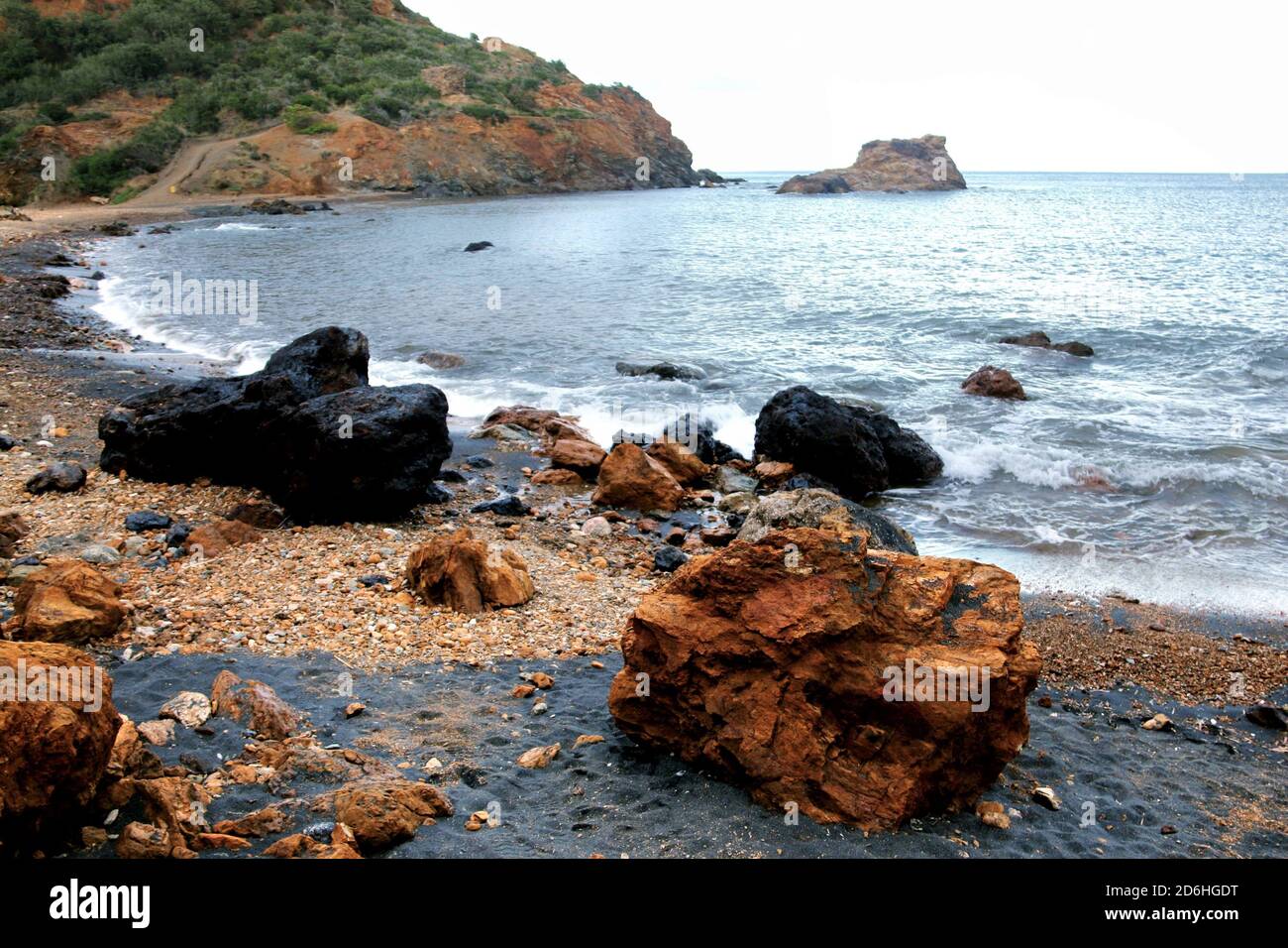 Spiaggia reale all'Isola d'Elba. Molto specifico per sabbia nera e pietre rosso-nere. Foto Stock