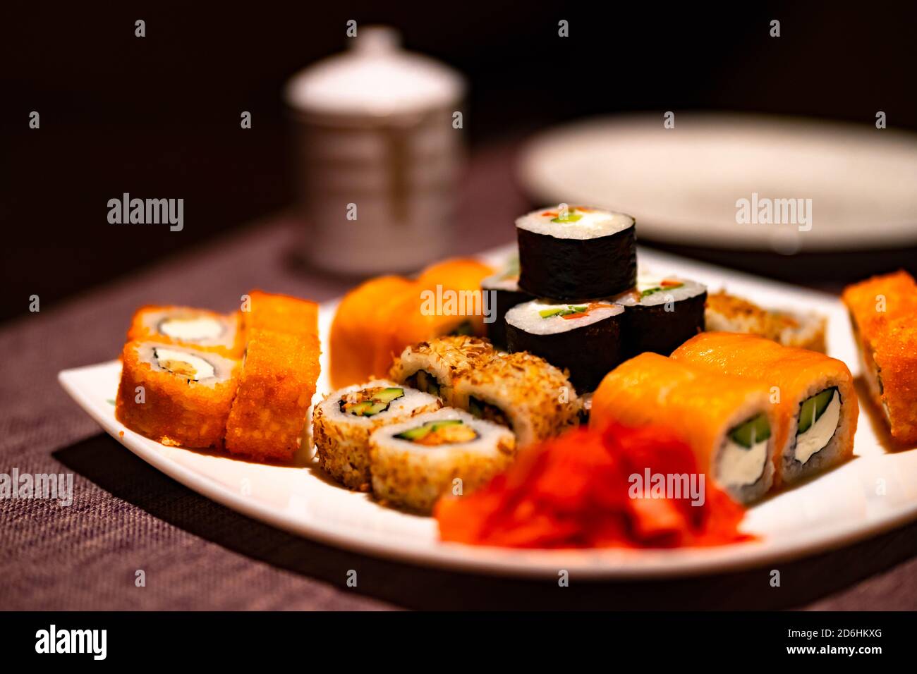 Serve appetitosi sushi su piatto bianco nel cafe. Primo piano di gustosi panini di sushi con wasabi e zenzero nel ristorante tradizionale giapponese. Foto Stock