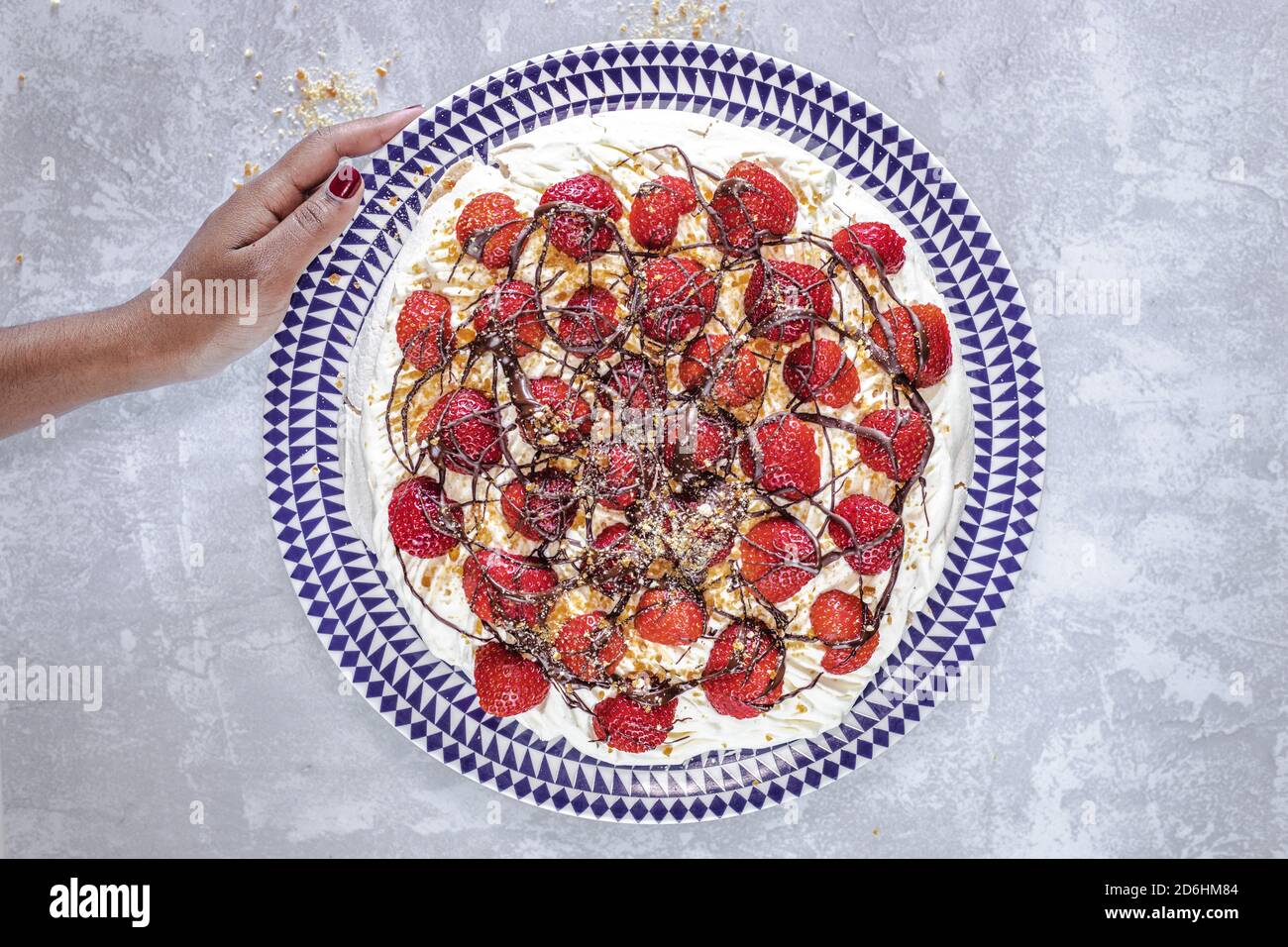 Pavlova decorata con fragole, cioccolato e pralina di cashew. Foto Stock