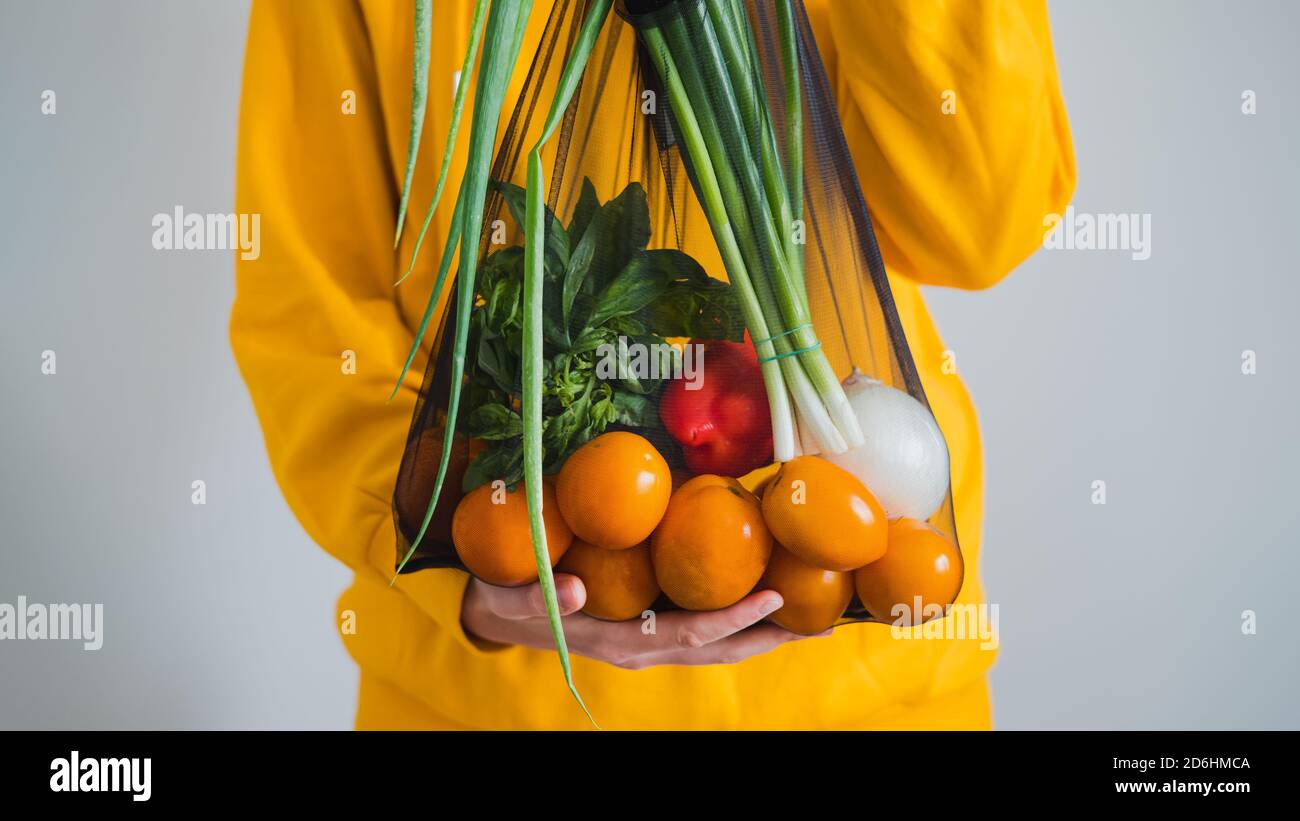 Sacchetto multiuso sostenibile di verdure biologiche dell'agricoltore. Donna tiene borsa della spesa con verdure e pomodori, concetto di cibo biologico shopping, na Foto Stock