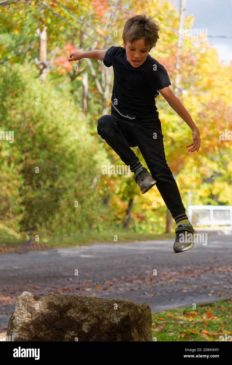 Un ragazzo atletico di 8 anni che salta in alto nel aria Foto Stock