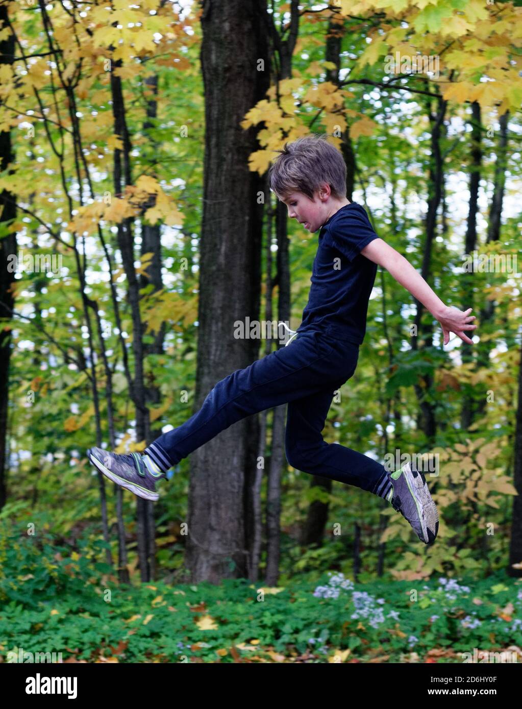 Un ragazzo atletico di 8 anni che salta in alto nel aria Foto Stock