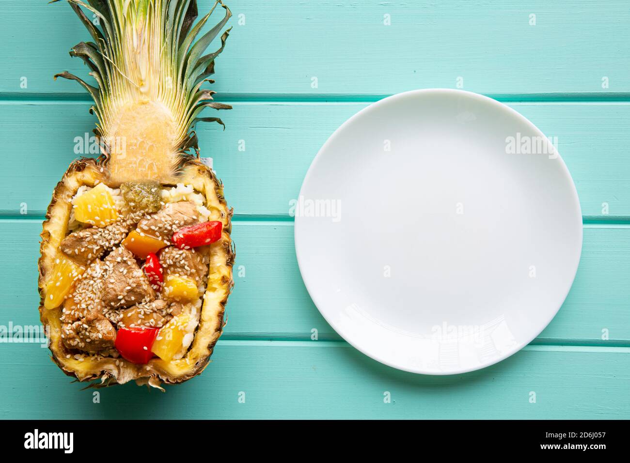 Riso all'ananas con pollo e verdure, vista dall'alto. Gustoso pasto esotico e piatto bianco vuoto. Cucina creativa. Foto Stock