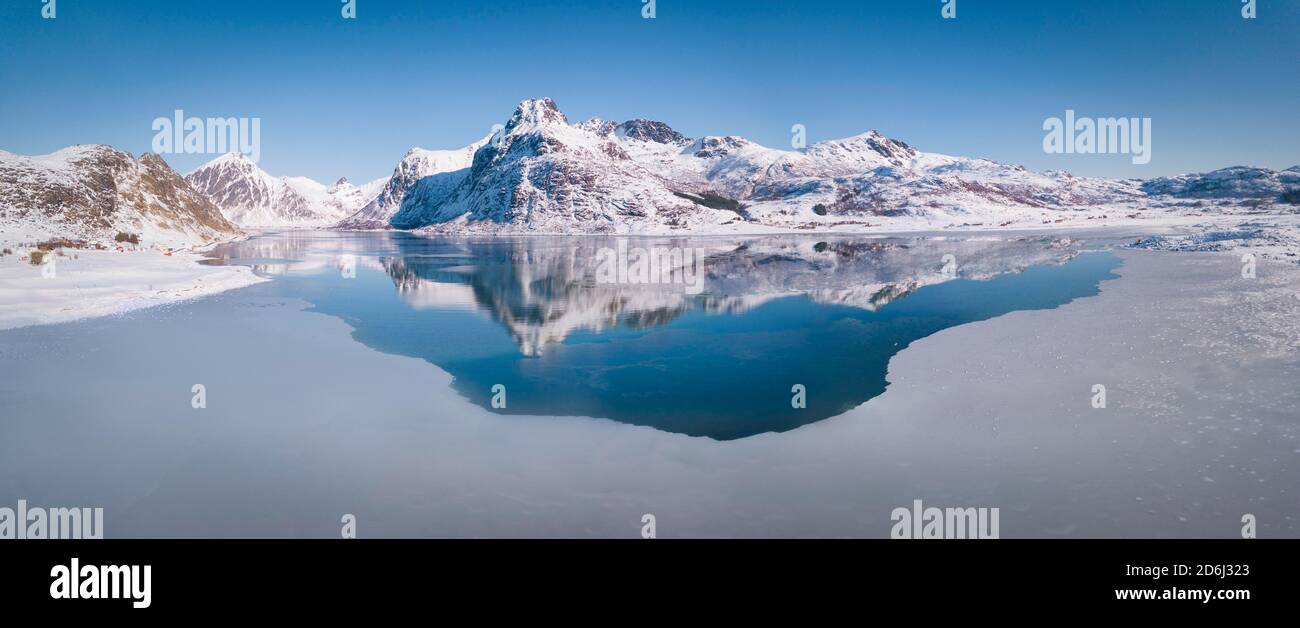 Vasta gamma di vini riflessi nel mare blu, grande strato di ghiaccio, dietro le montagne Blektinten e Andopshesten di fronte al fiordo Foto Stock