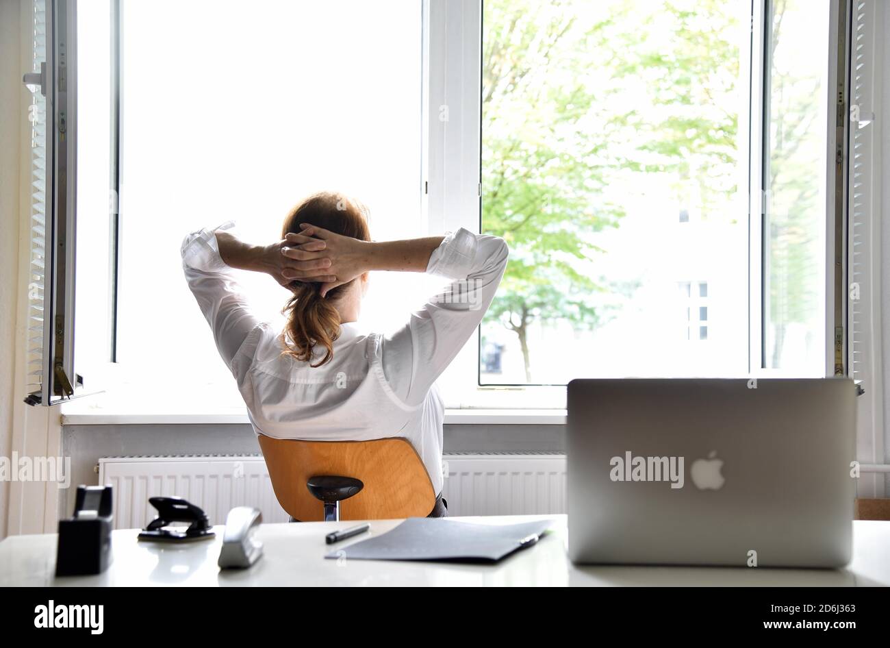 Donna seduta in ufficio con la finestra aperta, Germania Foto Stock