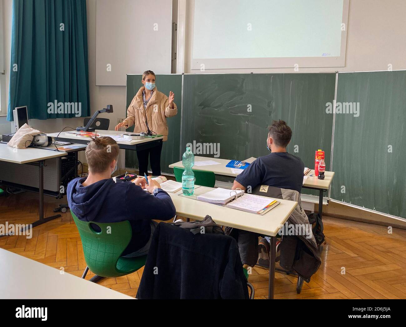 Insegnante con giacca invernale spessa e maschera facciale in aula insegnamento, gesti, crisi corona, Stoccarda, Baden-Wuerttemberg, Germania Foto Stock