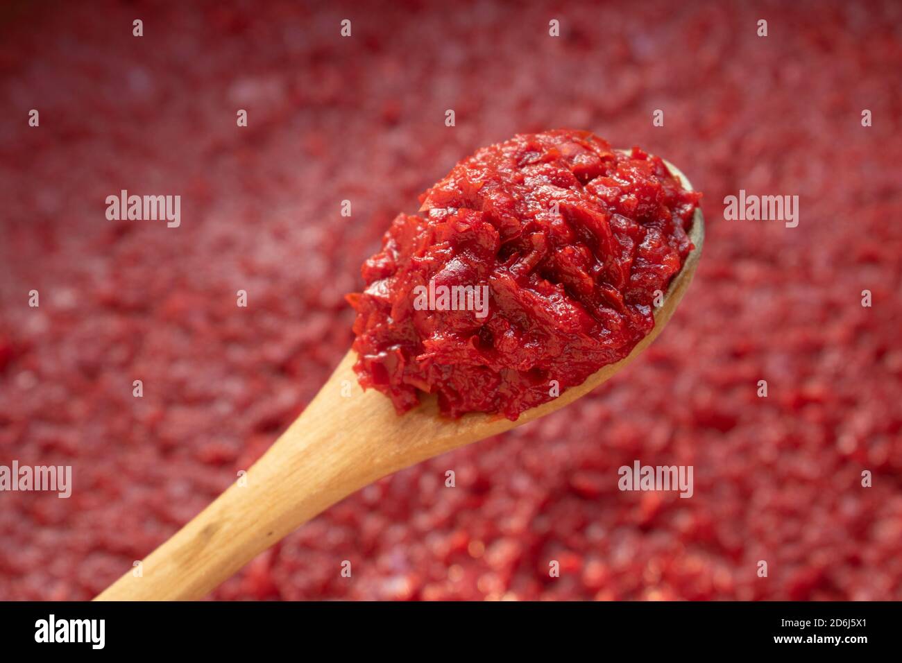 Pepare la pasta in un cucchiaio di legno su sfondo rosso Foto Stock