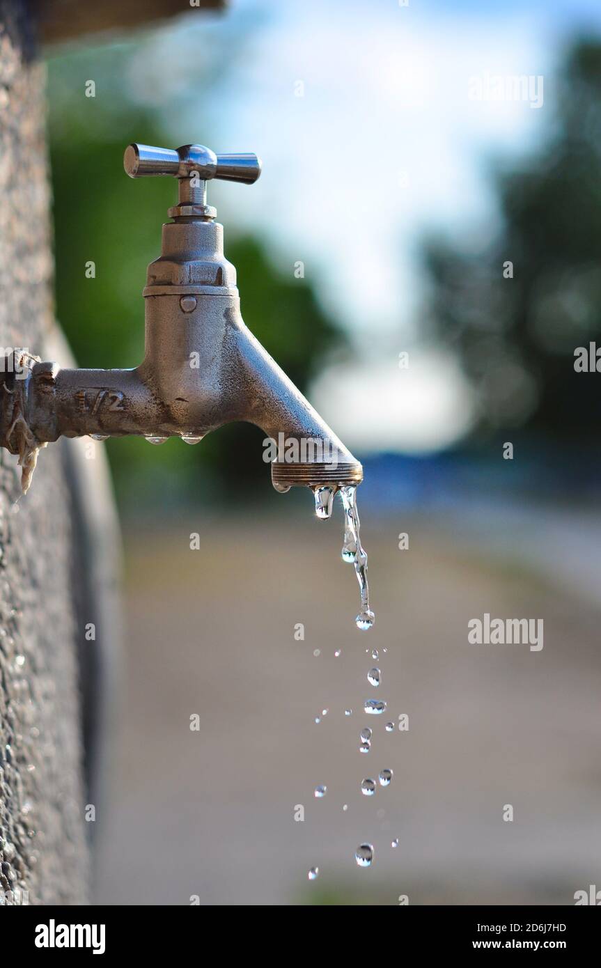 Acqua che gocciola dal rubinetto nel giardino, concetto di scarsità d'acqua Foto Stock