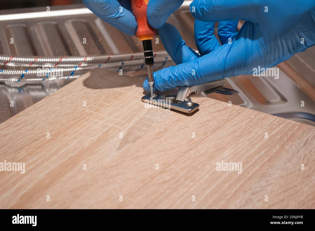 Montaggio della cerniera della portiera. Fissaggio a mano maschio,  riparazione di un attacco nella credenza della cucina, piccole riparazioni  a casa Foto stock - Alamy