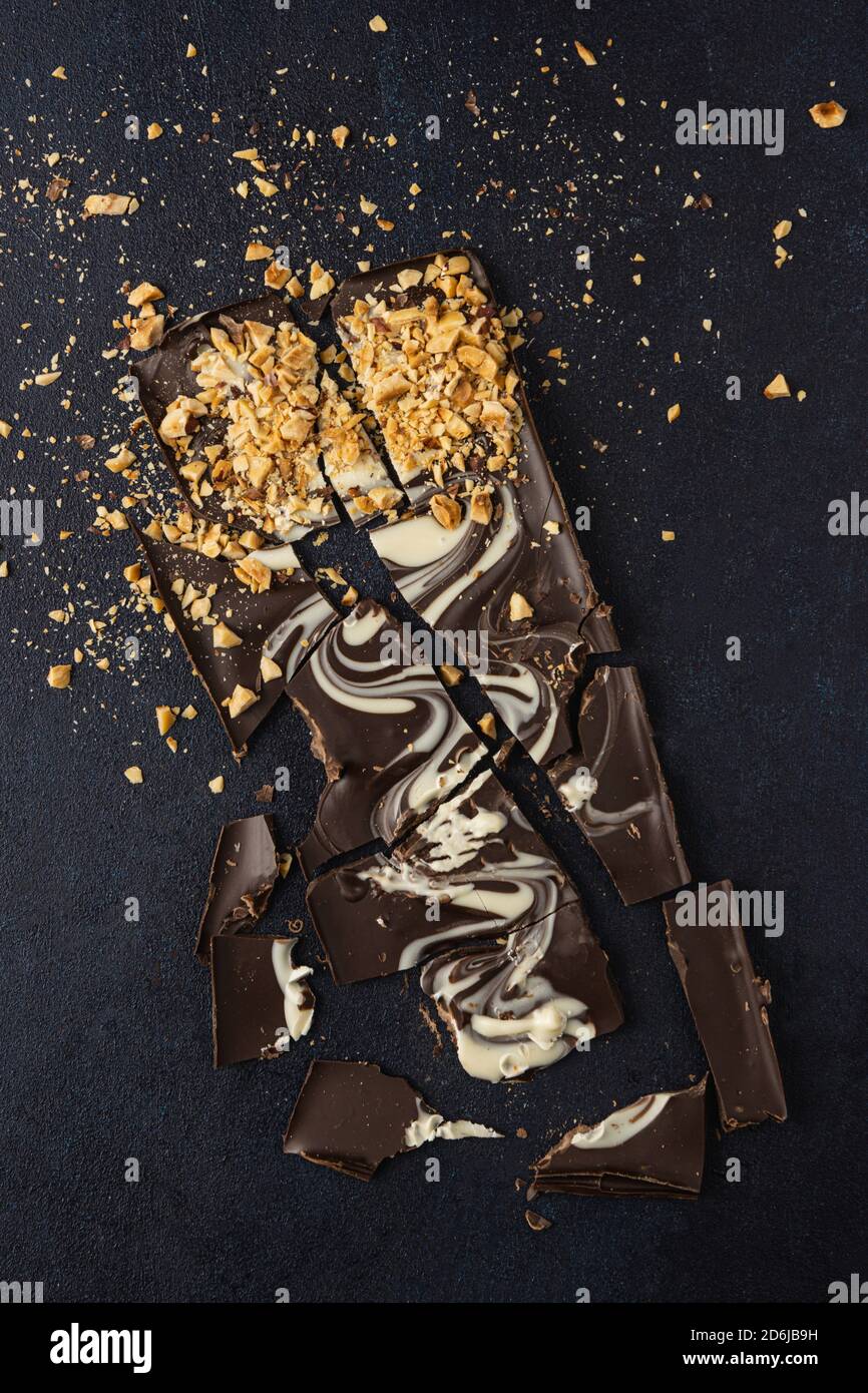 Corteccia di cioccolato scuro isolata su sfondo scuro. Vista dall'alto, disposizione piatta. Foto Stock