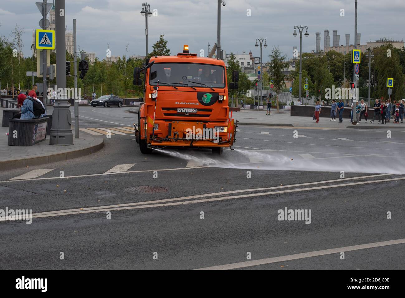 Mosca, Russia - 24 agosto 2020: Grande irrigatore arancione che attraversa un incrocio. Pulizia della strada della città di shanumen e wate Foto Stock
