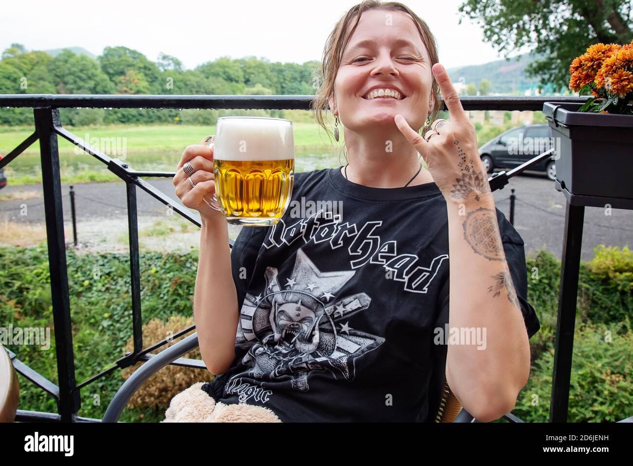 Decin, Repubblica Ceca, 18 agosto 2020: Fan femminile della band Motorhead con birra ceca seduto nel pub-giardino godendosi e sorridendo Foto Stock