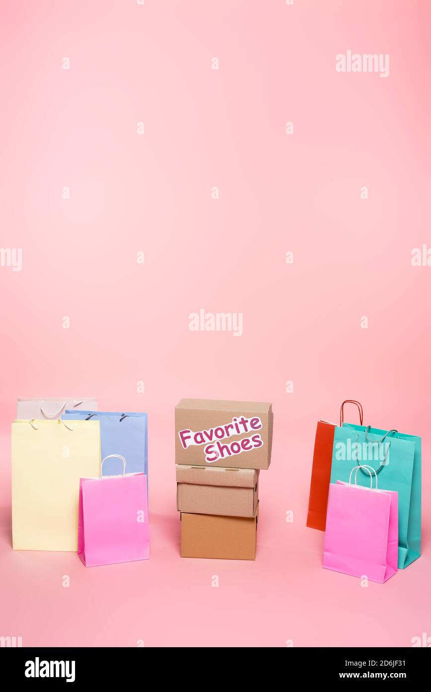 scatola di cartone con le scritte preferite delle scarpe vicino alle borse della spesa sul concetto rosa, nero del venerdì Foto Stock