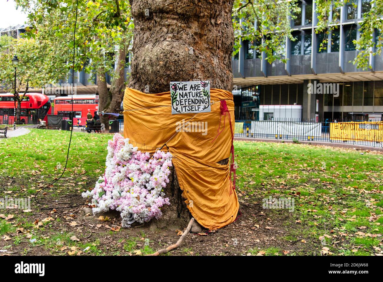 Londra, Regno Unito. 17 Ott 2020. Un albero avvolto in un foglio e ha avuto fiori messi contro di esso da HS2 (alta velocità 2) membri della ribellione in Euston Square, Londra come protestano contro la distruzione di boschi a causa della costruzione del collegamento ferroviario ad alta velocità Credit: SOPA Images Limited/Alamy Live News Foto Stock