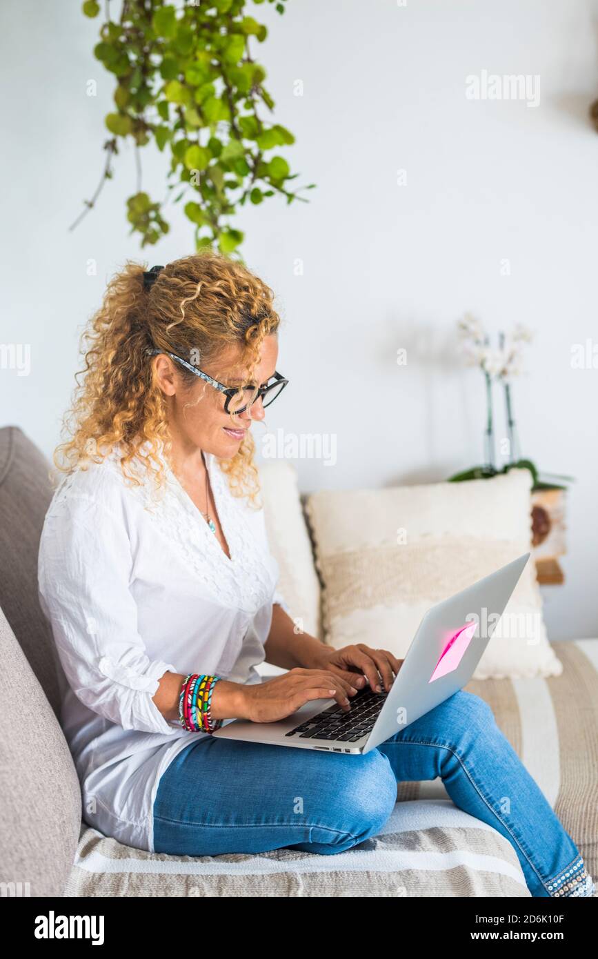 Bella donna lavoro e rilassarsi a casa con il computer portatile computer - concetto di lavoro intelligente e ufficio alternativo - le donne apprezzano la tecnologia sul divano Foto Stock