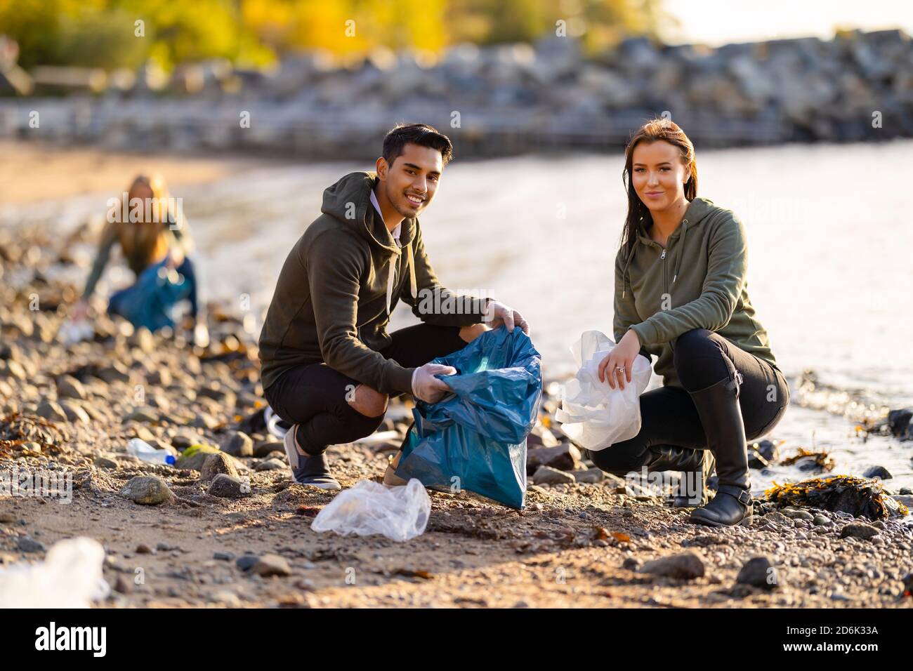 Ritratto di giovani volontari sorridenti che puliscono la spiaggia per la plastica Foto Stock