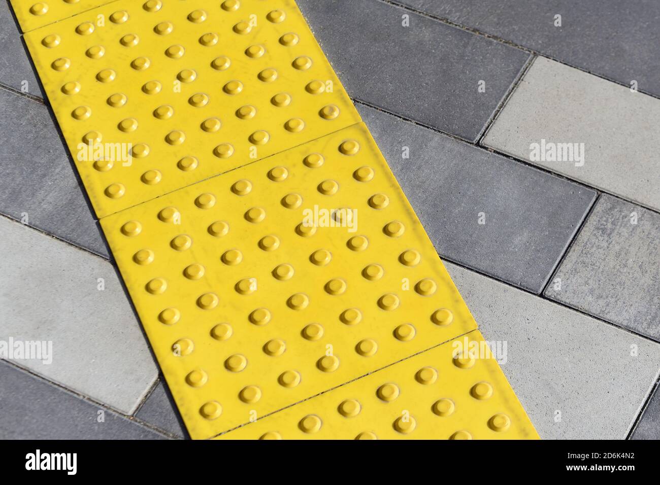 Blocchi gialli di pavimentazione tattile per handicap cieca. Blocchi di Braille, piastrelle tattili per non vedenti, blocchi Tenji. Superficie a terra ruvida Foto Stock
