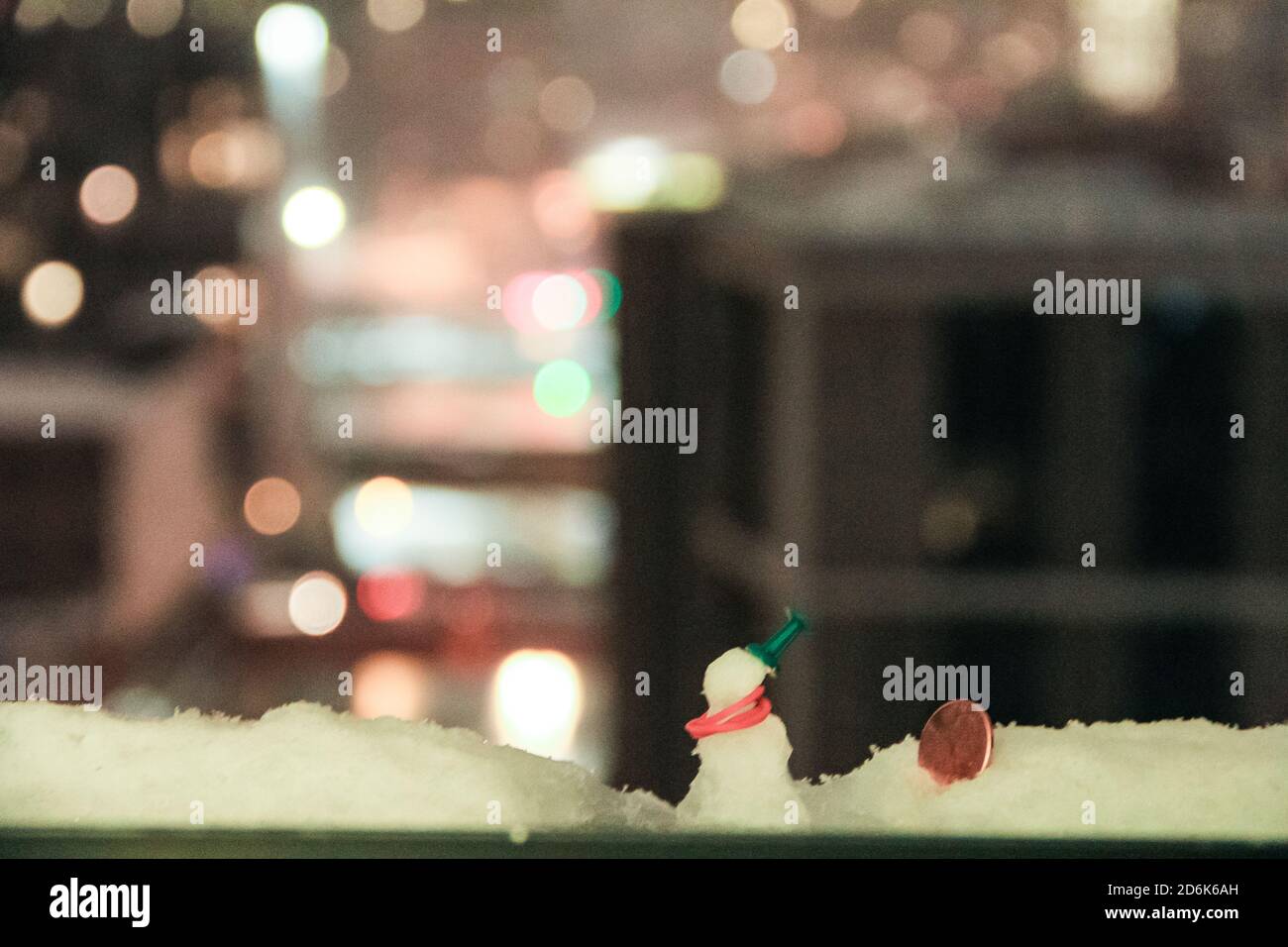 bokeh luci grattacieli città di new york con uomo neve in miniatura sul davanzale whimsical nevoso notte tempo 2 Foto Stock