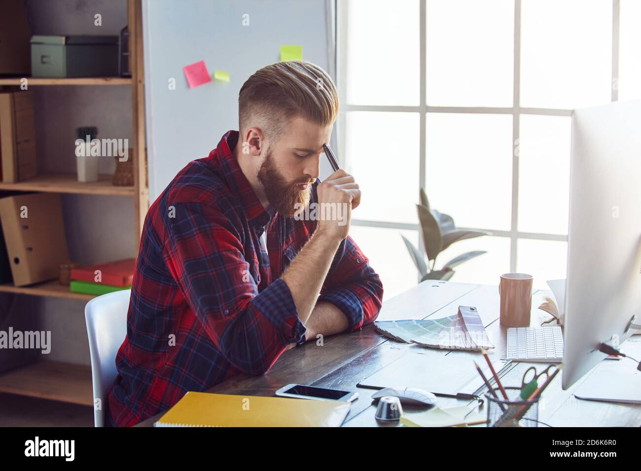 Giovane uomo che lavora su un tablet digitale professionale e un computer portatile con un campione di colore sulla scrivania in studio. Concetto di design creativo Foto Stock