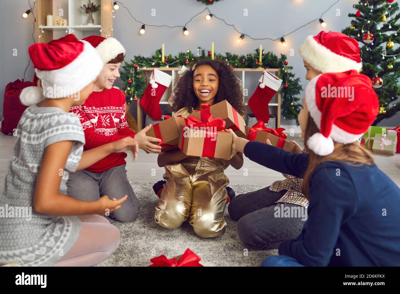 Gruppo di bambini danno doni alla sua fidanzata durante la celebrazione del Natale a casa. Foto Stock