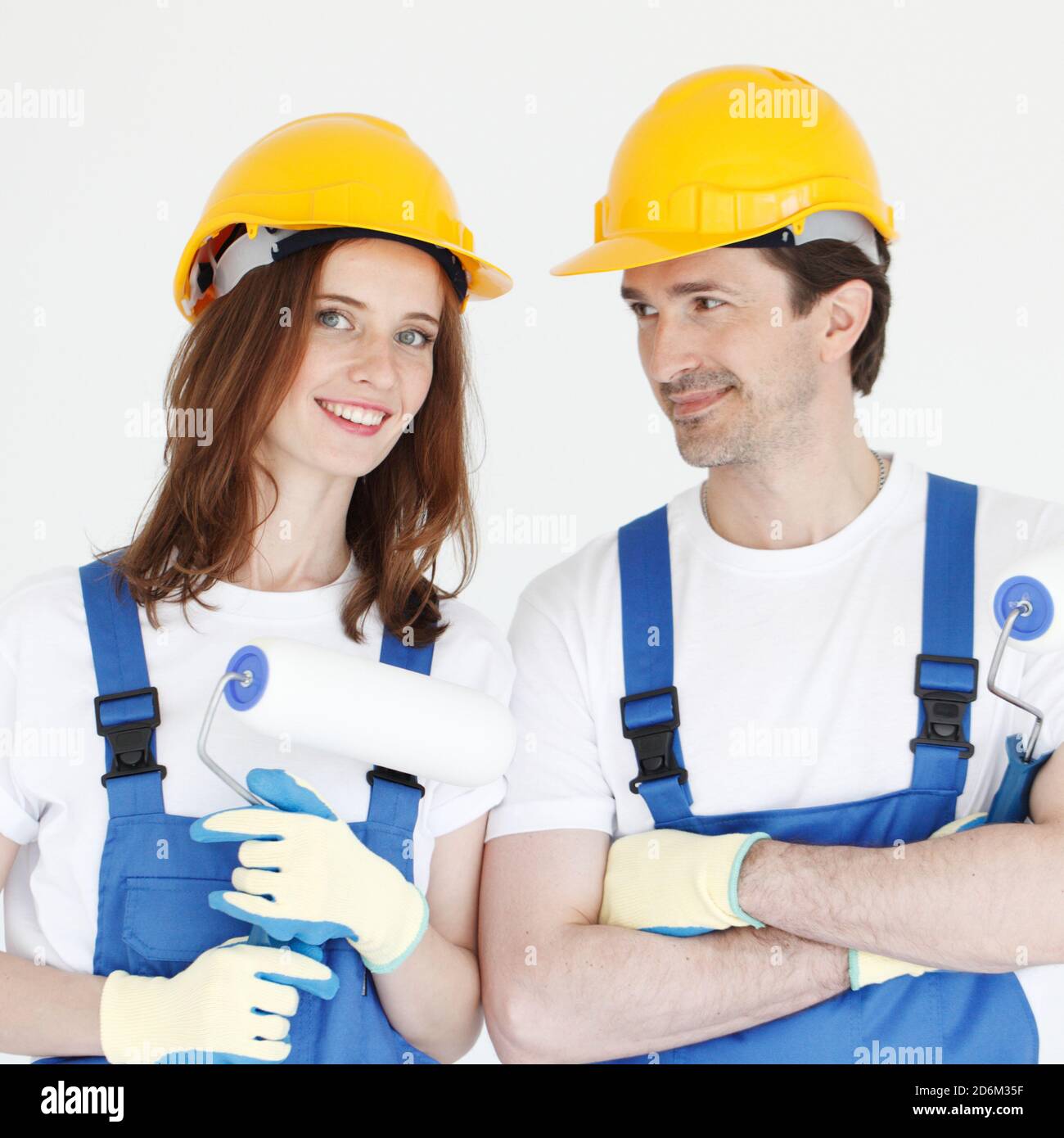 Due giovani lavoratori in uniforme di tuta e cappello con rulli di verniciatura Foto Stock