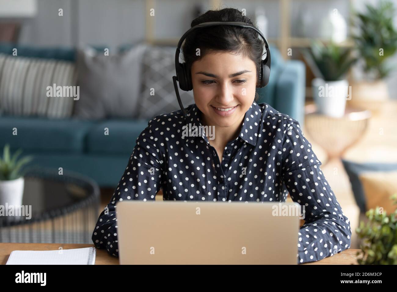 Donna indiana che indossa le cuffie partecipa a un webinar didattico utilizzando un computer portatile Foto Stock