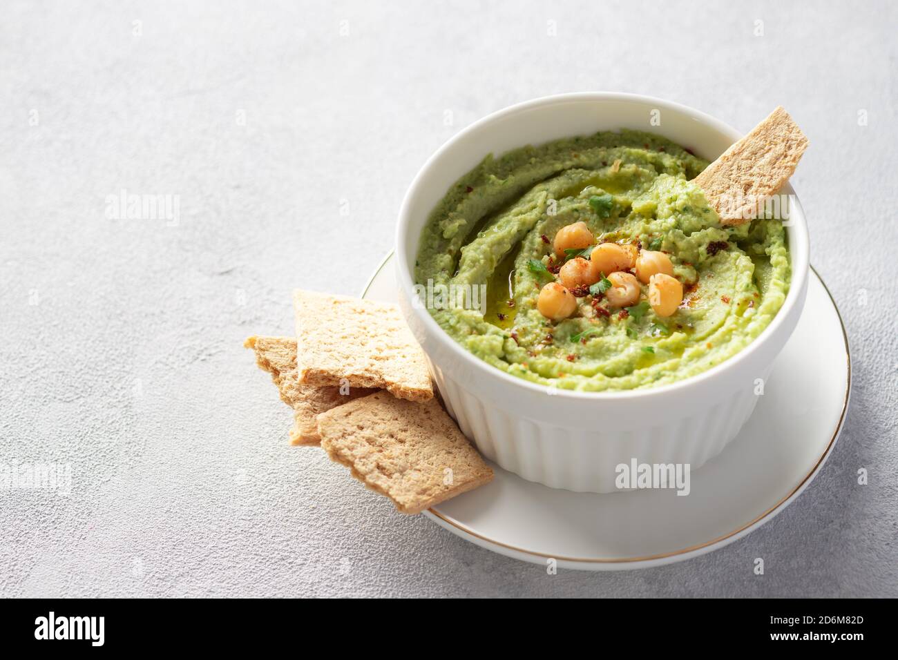 hummus all'avocado in ciotola bianca con ceci, prezzemolo, spezie e cracker di riso Foto Stock