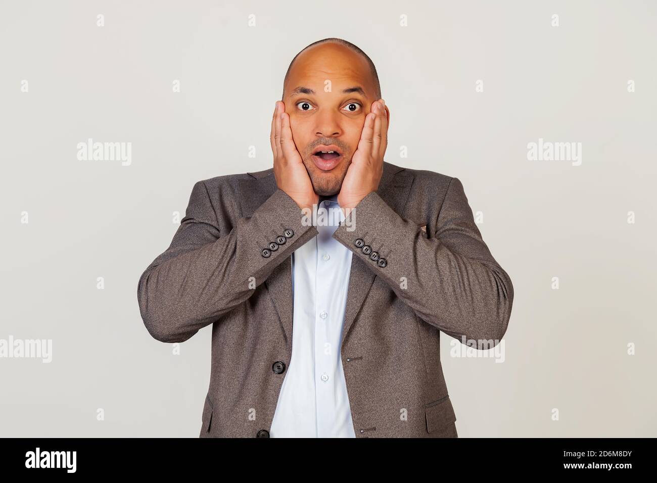 Scioccato giovane uomo d'affari afro-americano che esprime sorpresa e stupore, toccando il viso e piegando le labbra, si alza in uno stupore e occhiali alla macchina fotografica, essendo impressionato Foto Stock