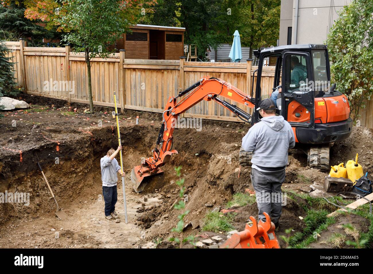 L'appaltatore misura la profondità del foro scavato da un escavatore in Un cortile posteriore per una piscina in Barrie Ontario Foto Stock