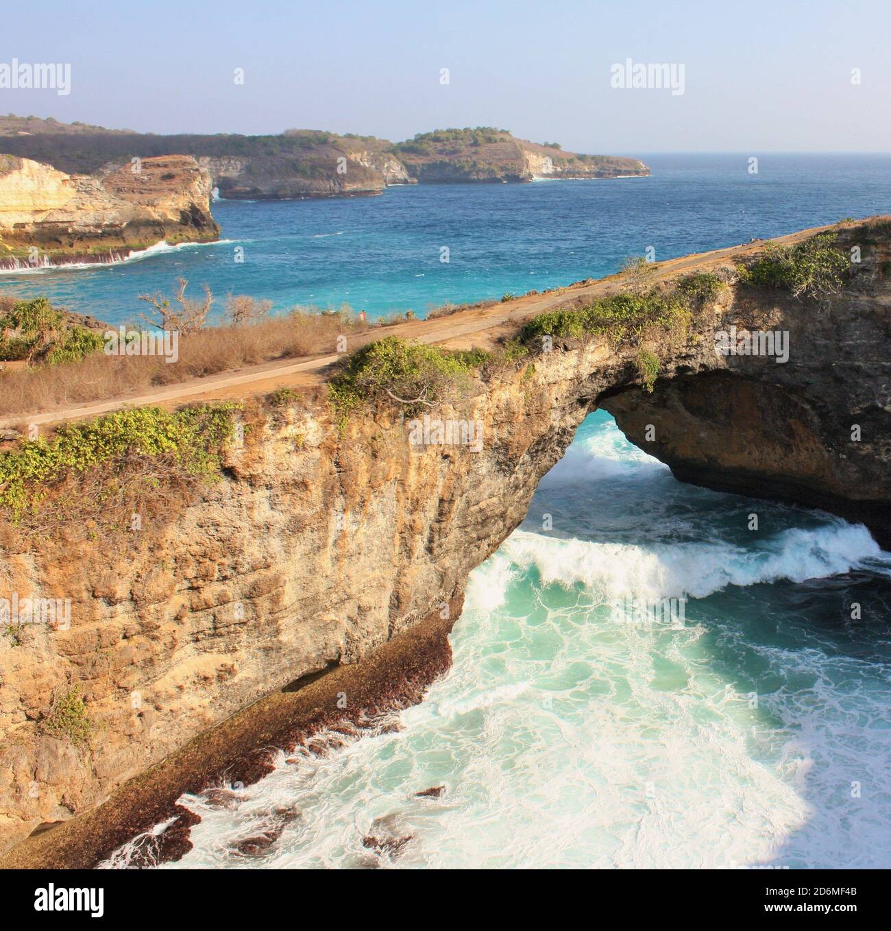 Onda che scorre sotto l'arco naturale scenico a Broken Beach, Nusa Penida, Indonesia Foto Stock