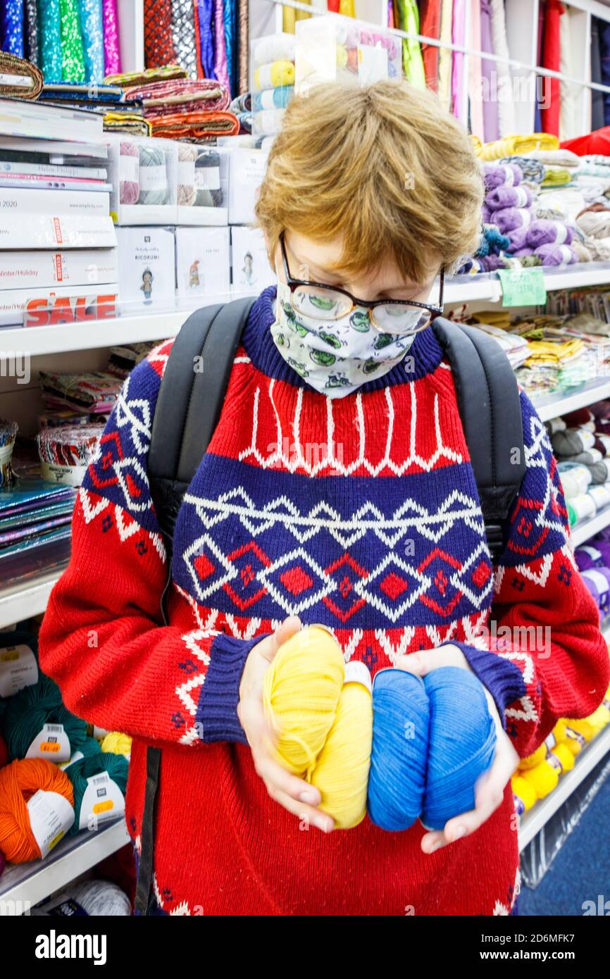 Una giovane donna caucasica in un ponticello di lana con motivi luminosi, brilla per lana e motivi in un negozio di artigianato, Londra, Regno Unito Foto Stock