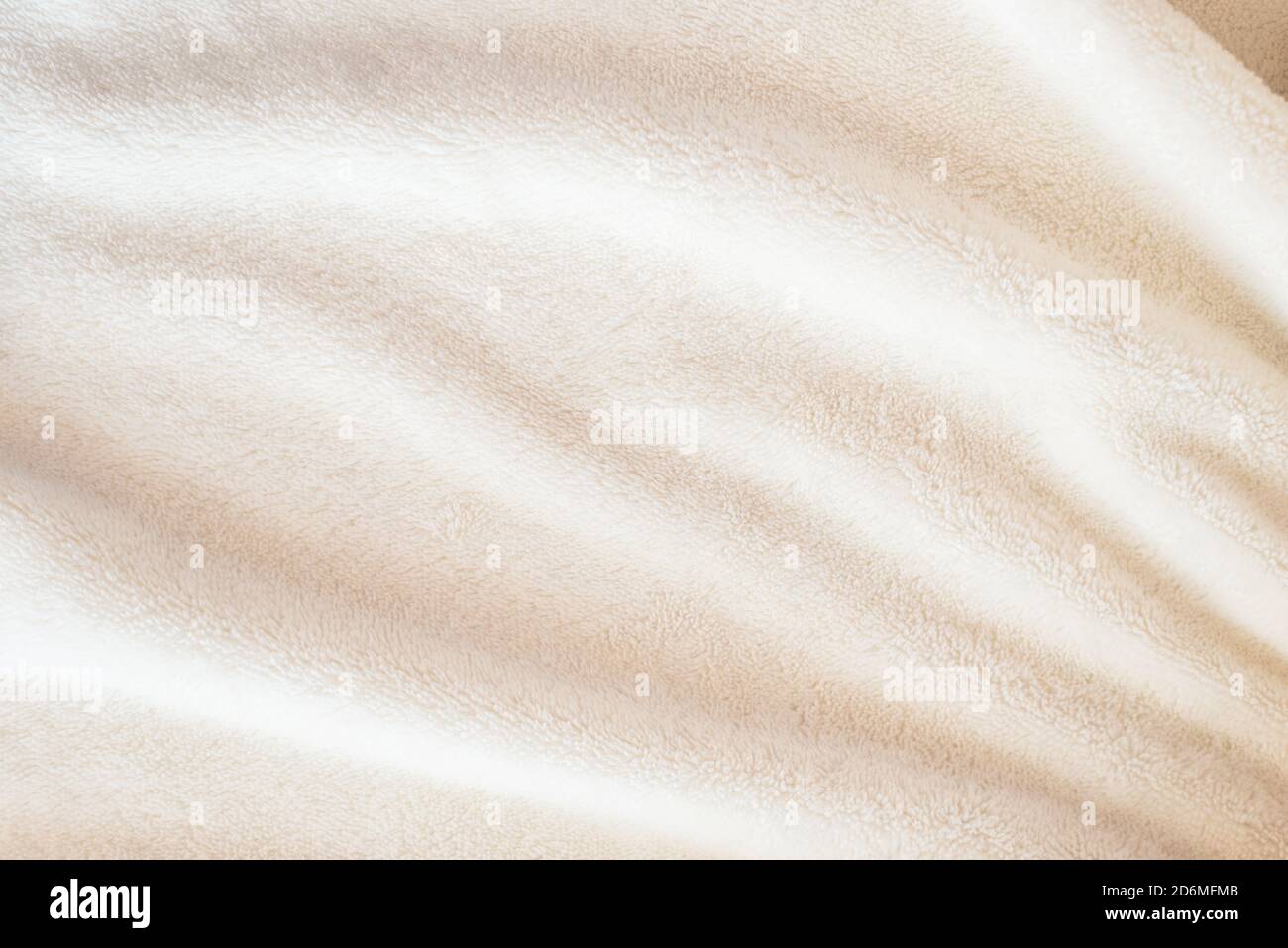 Un morbido e accogliente plaid fatto di tessuto bianco con un pile giace in belle pieghe Foto Stock