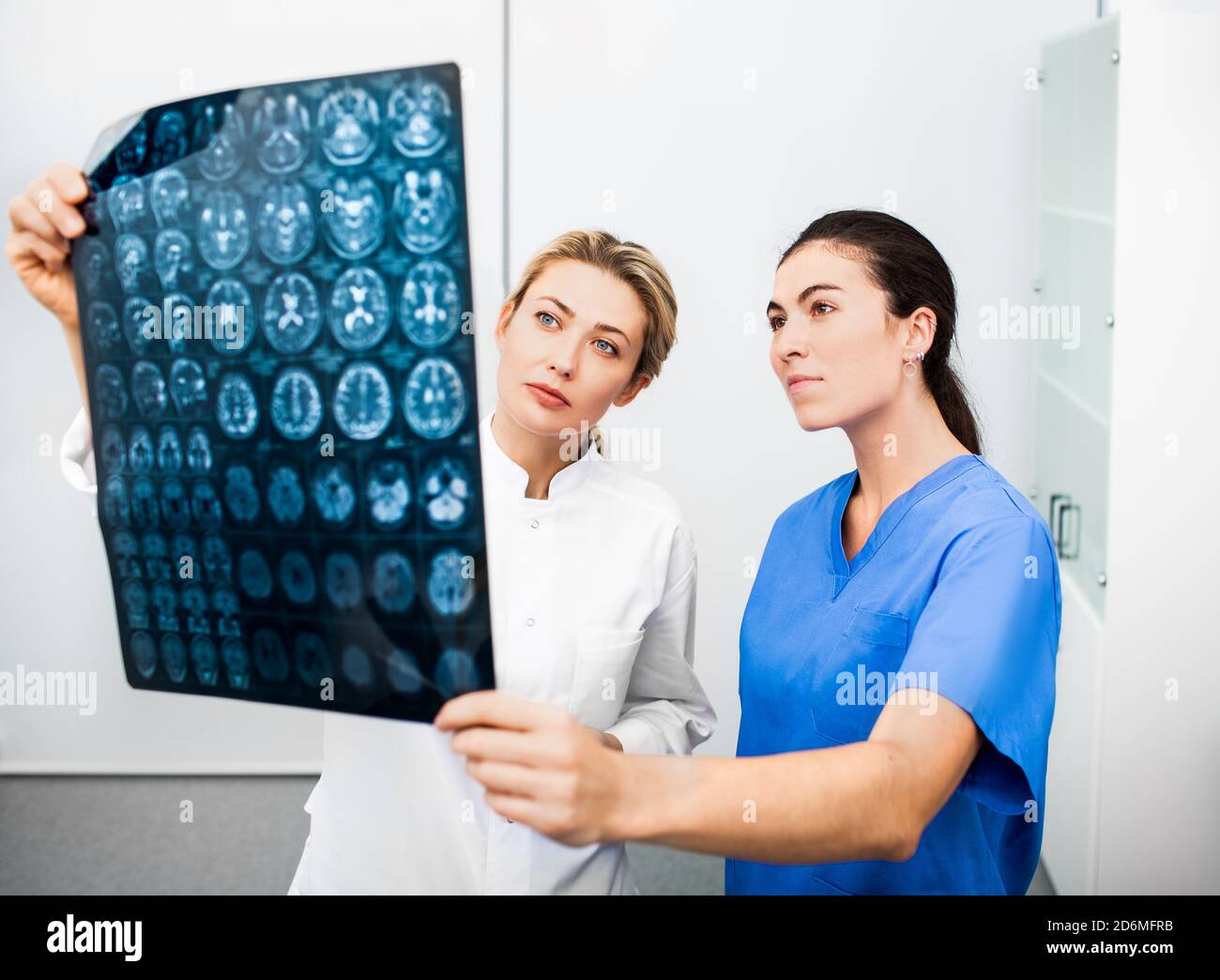 Neurologo e radiologo donna esperto stanno esaminando una scansione RM della testa di un paziente. Diagnostica e trattamento di malattie cerebrali, mal di testa, Foto Stock