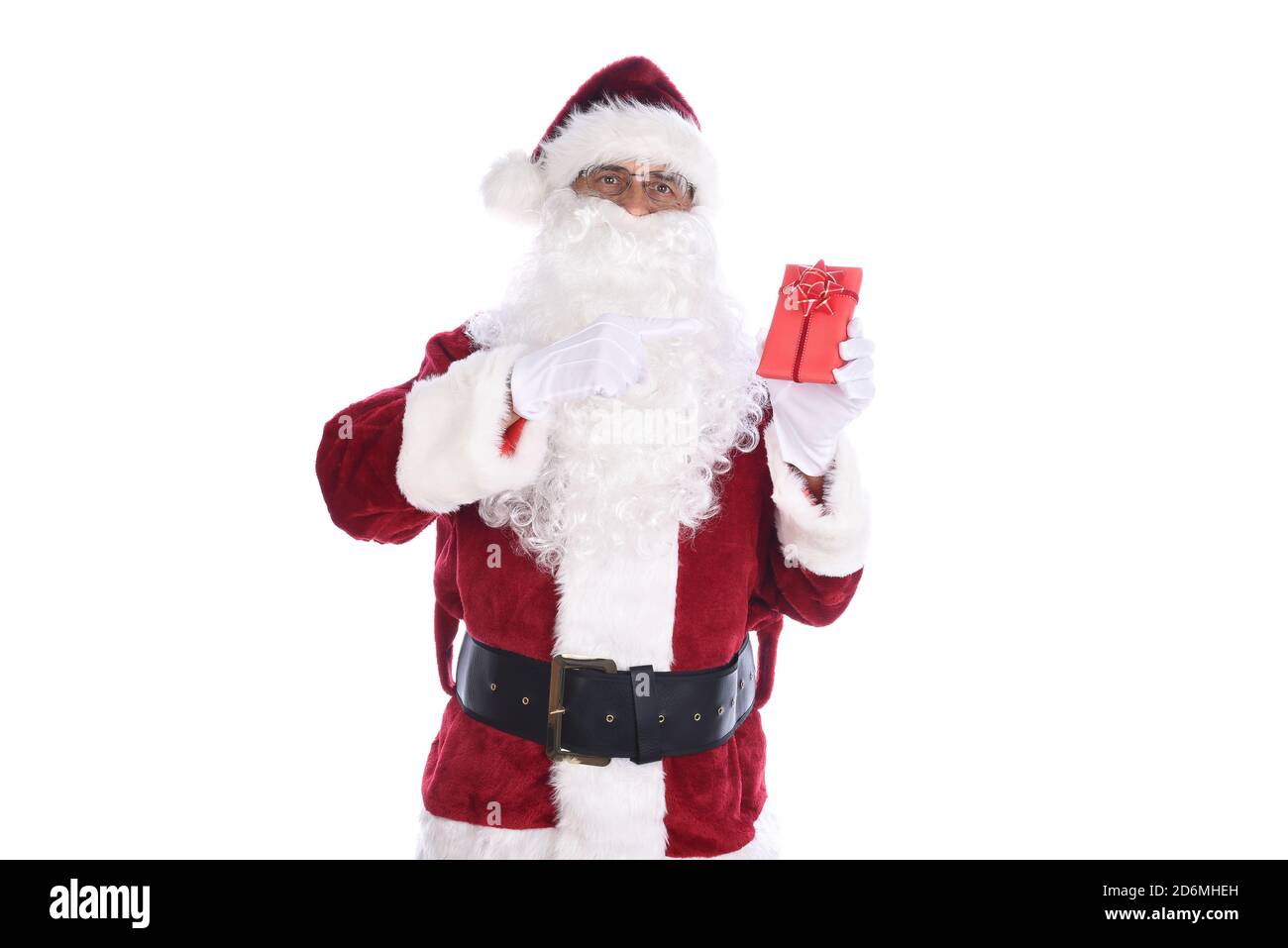 Uomo anziano che indossa un costume tradizionale di Babbo Natale che tiene un piccolo regalo di carta rossa avvolto in una mano e che lo indica con l'altra. Isolato o Foto Stock