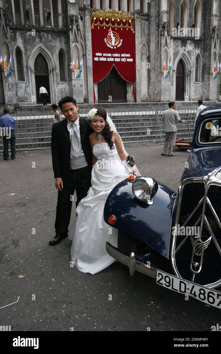 Posa pre-matrimonio di una giovane coppia vietnamita con una classica vettura Citroen Traction Avant di fronte alla Cattedrale di San Giuseppe ad Hanoi, in Vietnam. Foto Stock