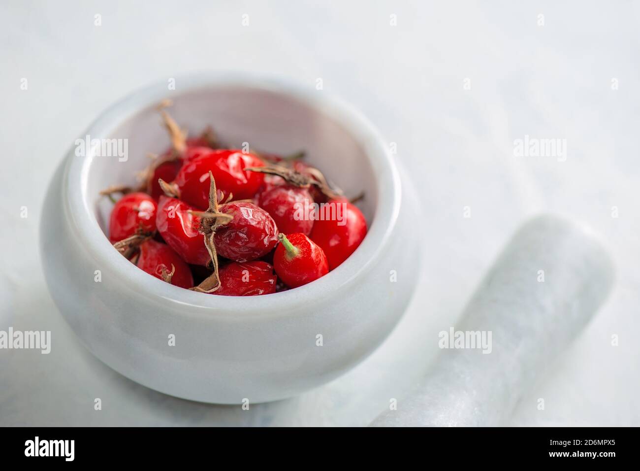 anche di rose mature in un mortaio di pietra e pestello. Rosehip sarà schiacciato per fare il tè della vitamina. Foto Stock