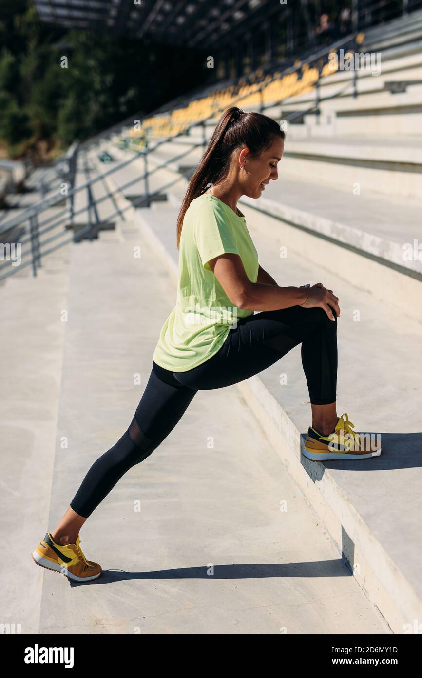 Fitness giovane donna che allunga le gambe allo stadio Foto Stock