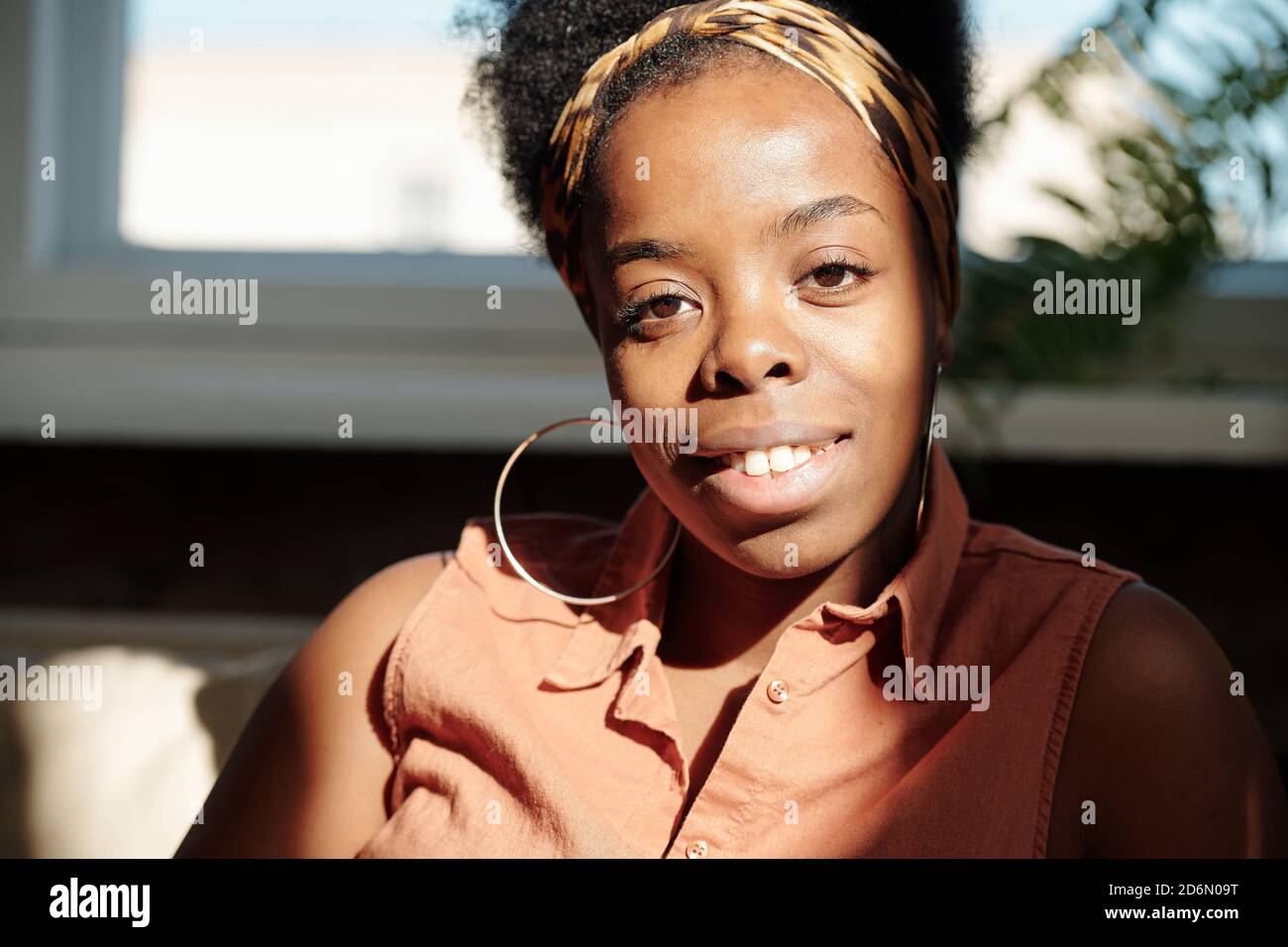 Giovane allegra donna di etnia africana che ti guarda con sorrisi Foto Stock