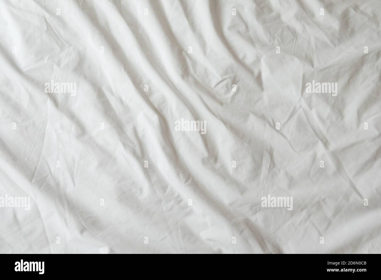 Sfondo di fogli bianchi. Biancheria da letto con rughe nella luce del giorno. Orizzontale. Spazio di copia. Concetto di riposo, risveglio, sonno, soggiorno a casa. Per Foto Stock