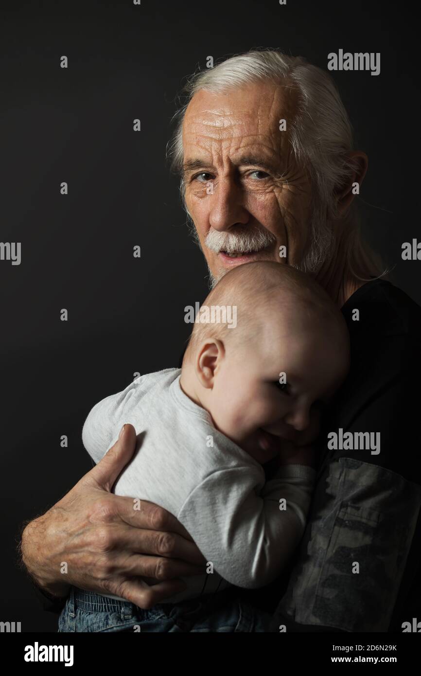 Ritratto in studio a basso tasto di sorridenti attraenti capelli grigi, vecchio e piccolo bambino. Verticalmente. Foto Stock