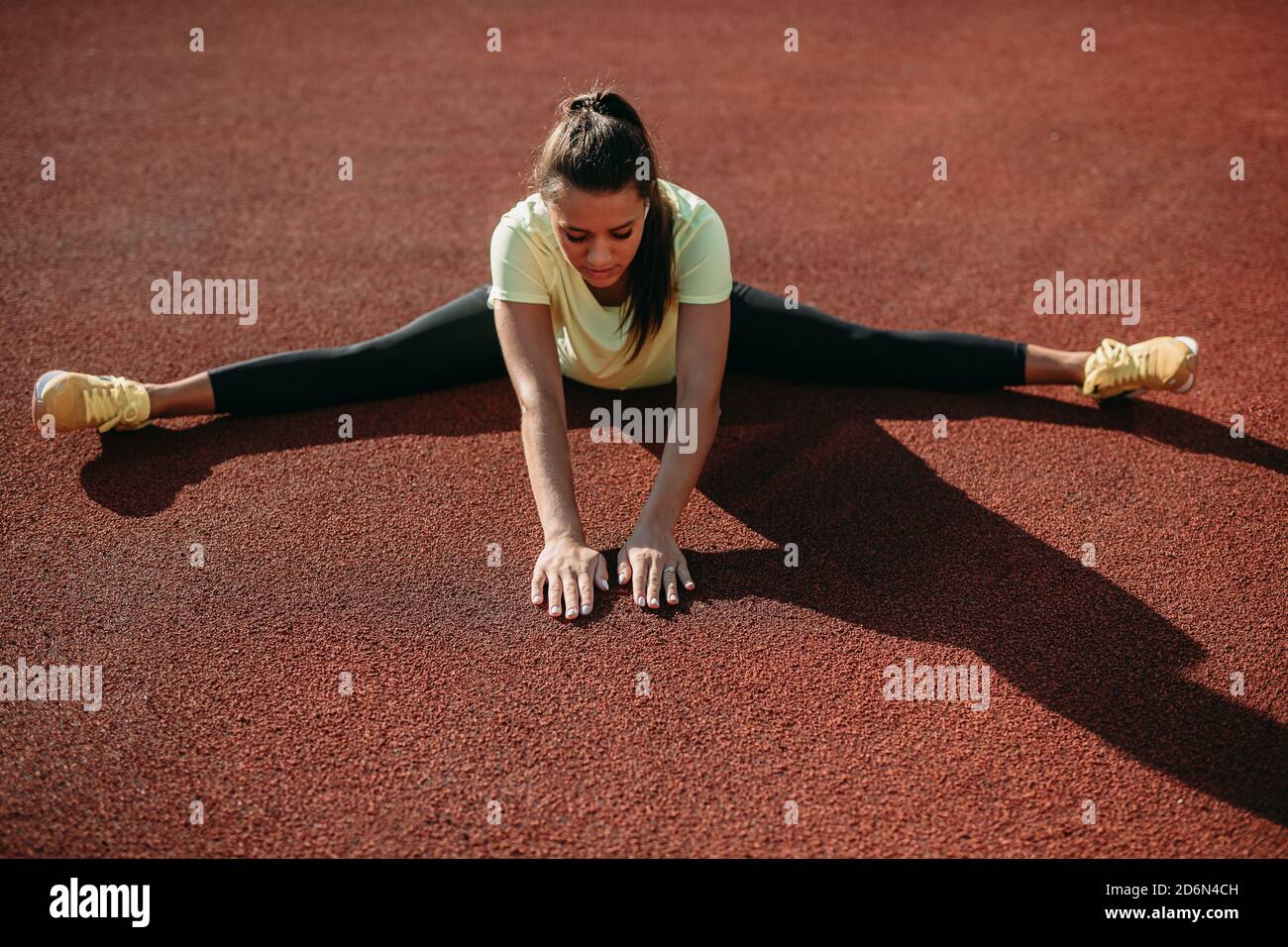 Giovane donna persistente che allunga i muscoli dopo l'allenamento Foto Stock Giovane donna persistente che allunga i muscoli dopo l'allenamento Foto Stock
